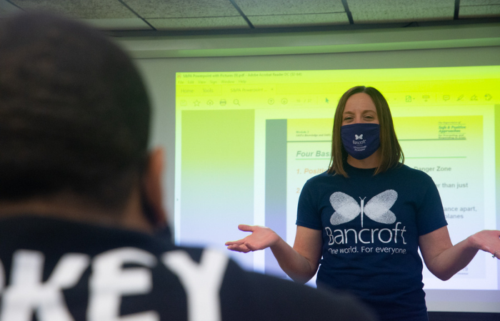 Jessica Marchese, employee at Bancroft, onboarding new employees standing in front of a projection screen.