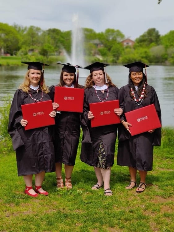 Four Rider graduates holding their diplomas.