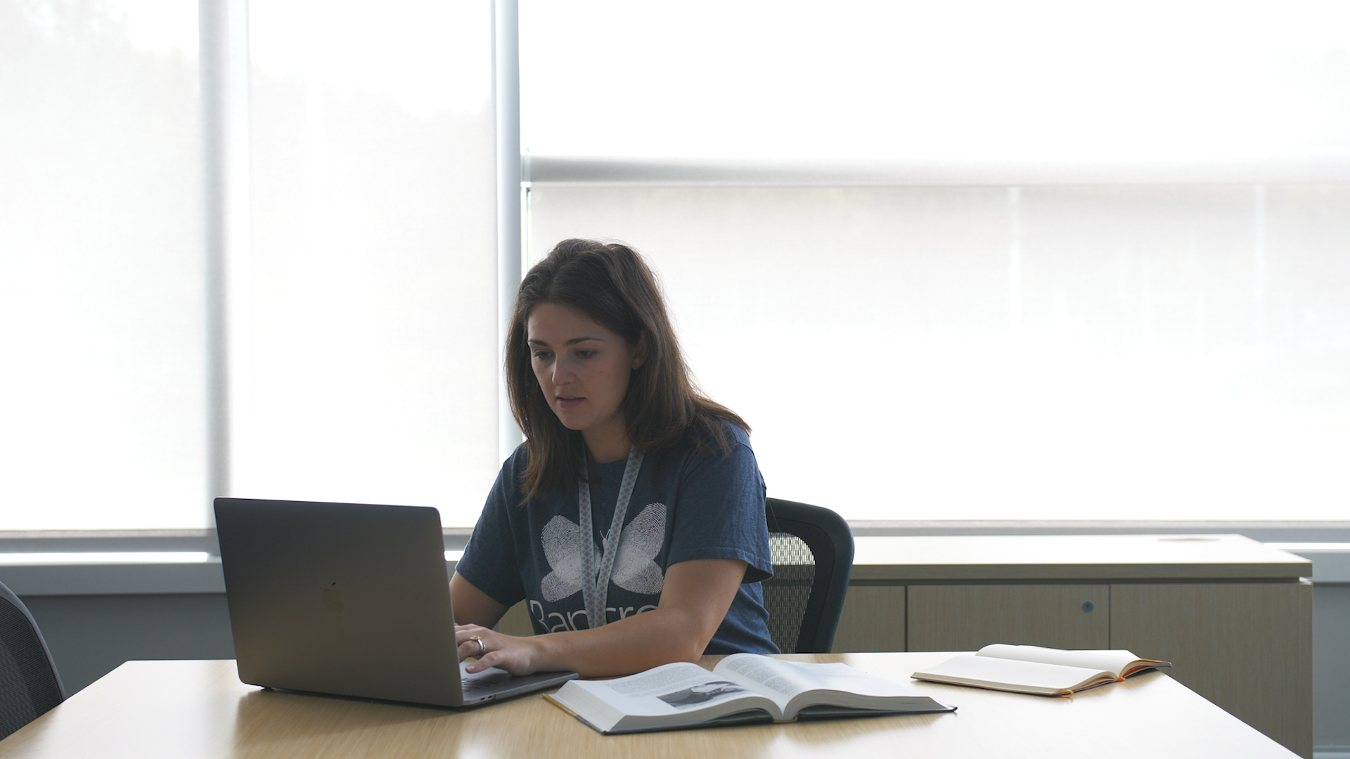 Bancroft employee wearing a gray shirt sitting by a table looking at their computer.